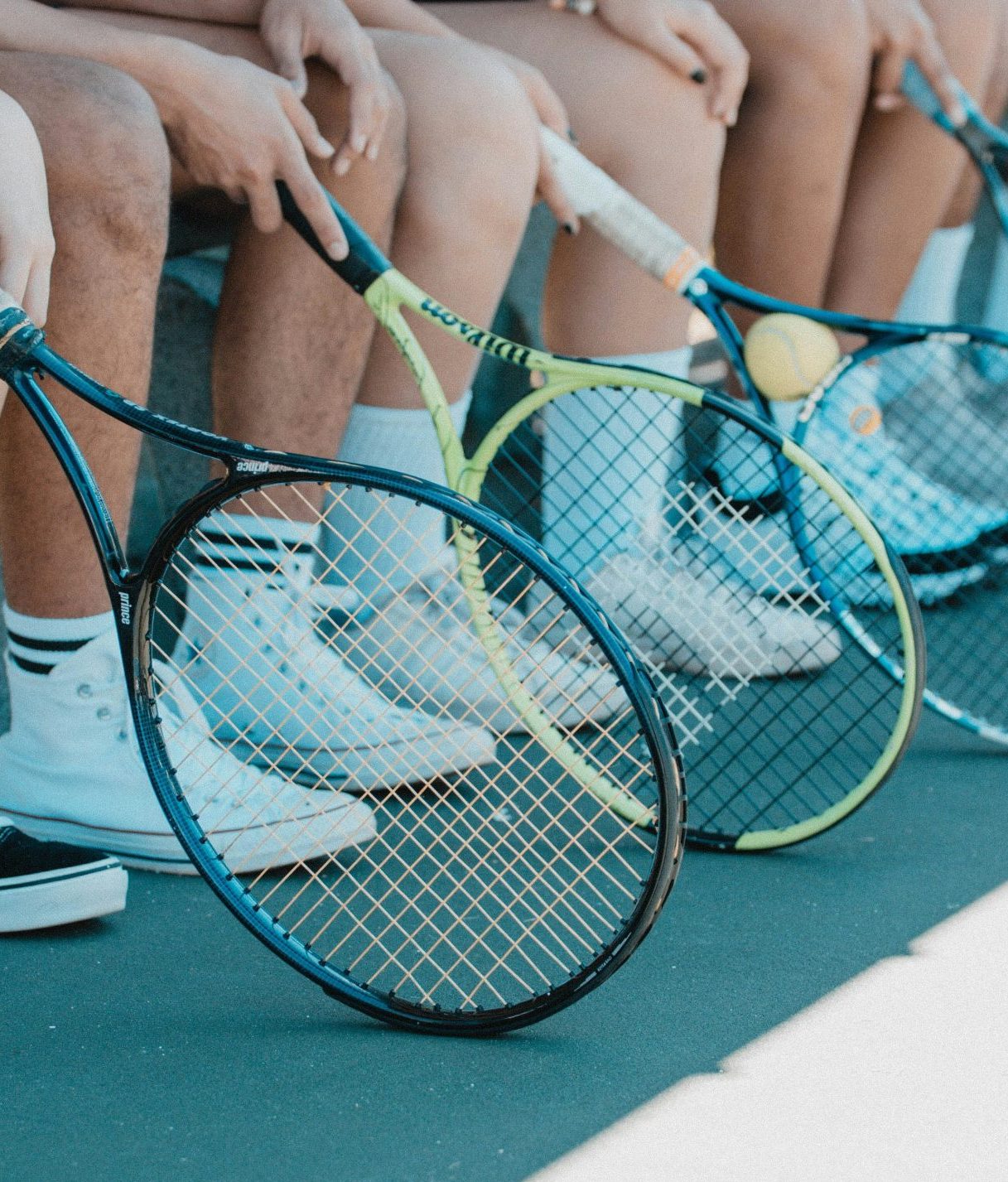 Kinder mit Tennisschläger sitzen auf einer Bank